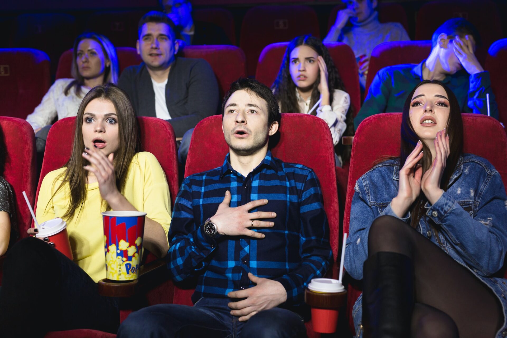 Group of people watch a horror movie at the cinema