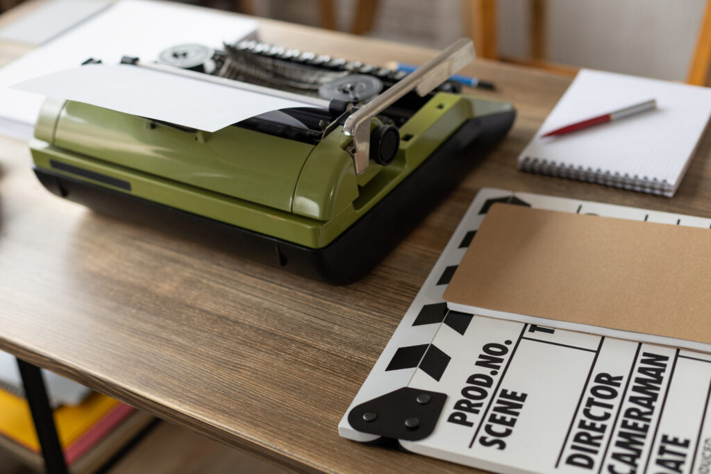 Clapper board and vintage typewriter at wooden desk table